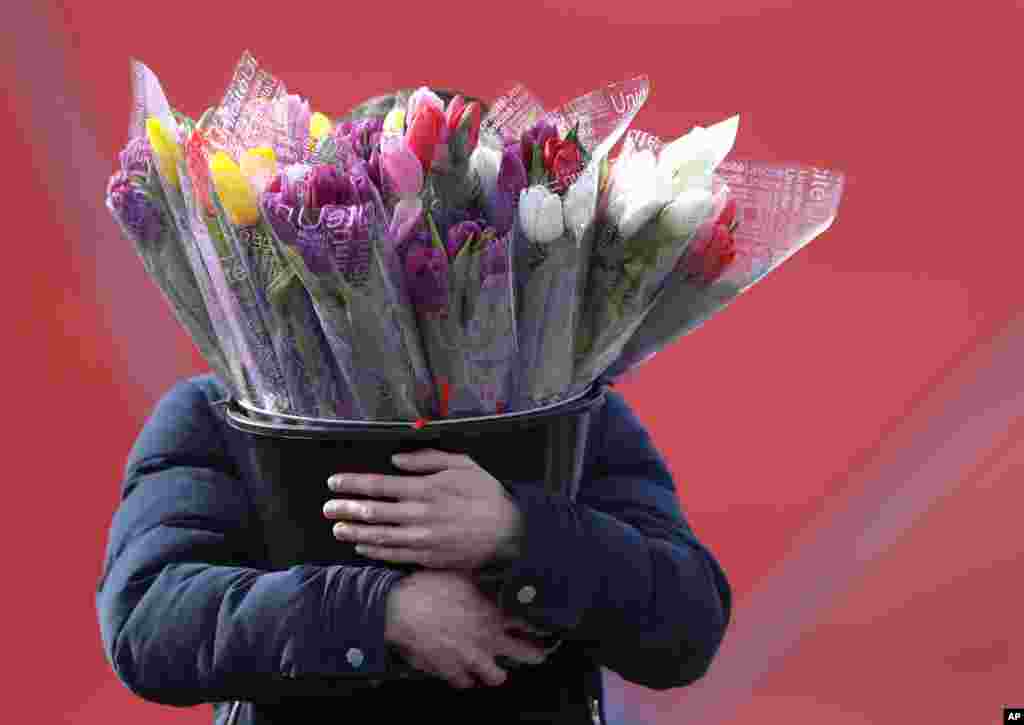 A man carries a bucket with bouquets of tulips at a street market on the eve of the International Women's Day in Minsk, Belarus.