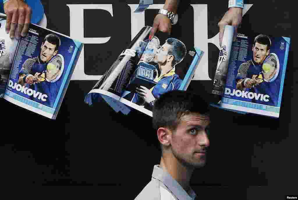 Novak Djokovic of Serbia walks past magazines featuring pictures of himself as he signs autographs after winning a men's singles match against Leonardo Mayer of Argentina, at the Australian Open 2014 tennis tournament in Melbourne, Australia.