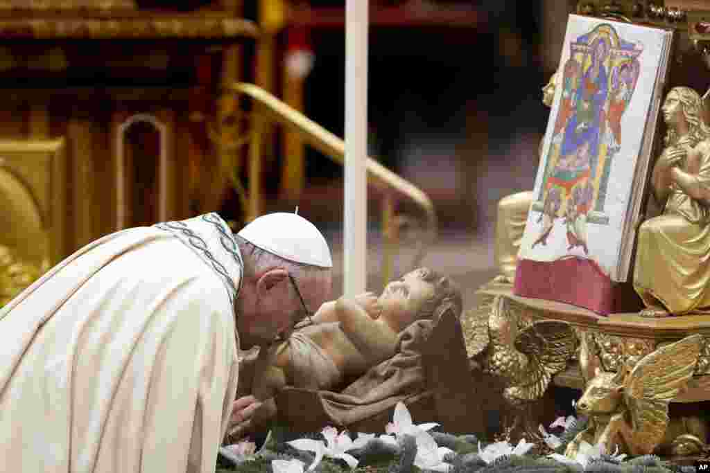 Pope Francis kisses a statue of Baby Jesus as he celebrates a New Year's eve vespers Mass in St. Peter's Basilica at the Vatican.