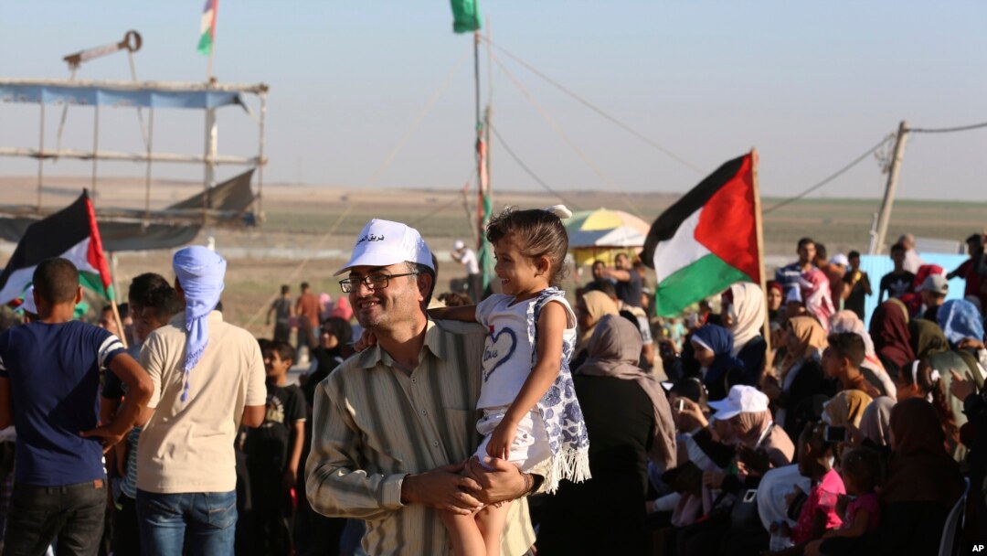 In this Sept. 25, 2019 photo, Palestinian activist Ahmed Abu Artima holds his daughter during an alternative protest he organized near the separation fence between the Gaza Strip and Israel.