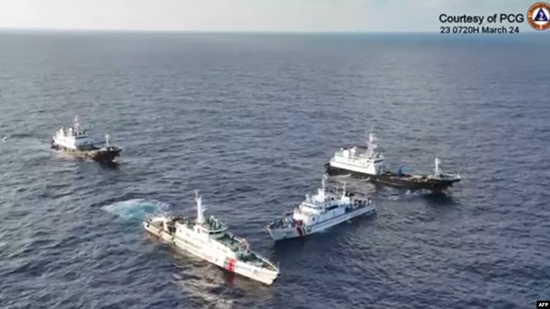 This frame grab from aerial video footage taken and released on March 23, 2024, by the Philippine coast guard shows Chinese vessels surrounding a Philippines coast guard ship near Second Thomas Shoal in waters of the disputed South China Sea.