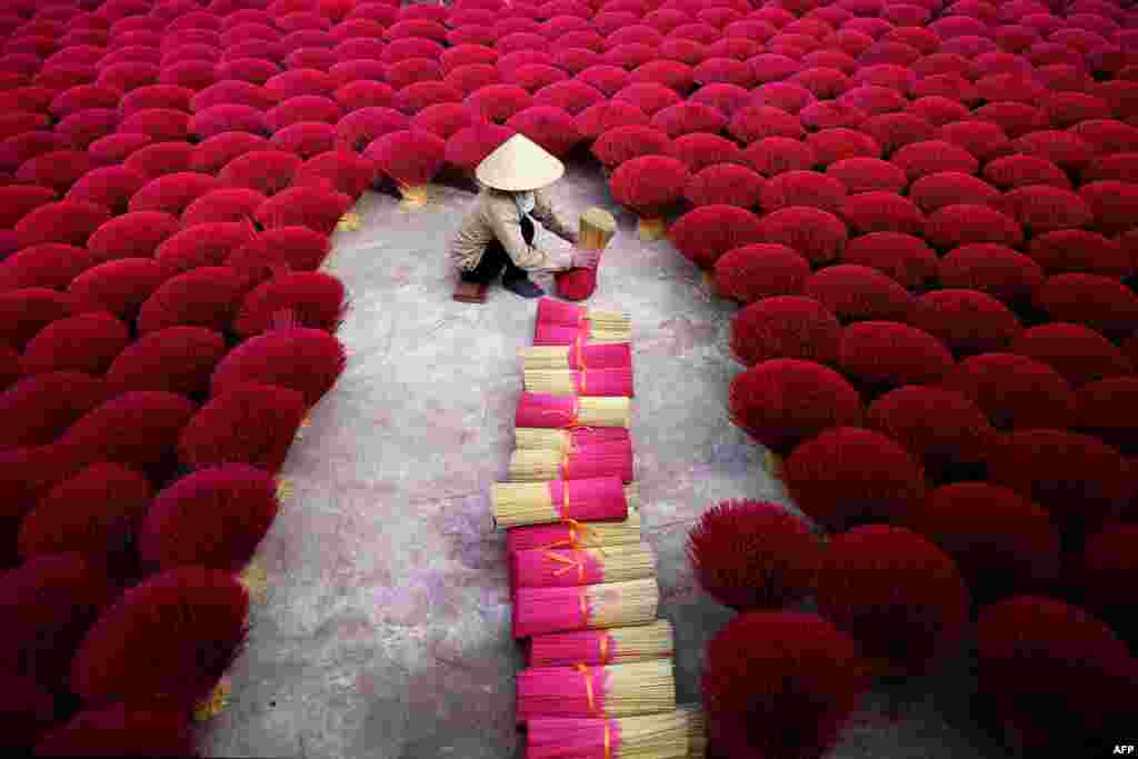 A Vietnamese woman collects incense sticks in a courtyard in the village of Quang Phu Cau on the outskirts of Hanoi.