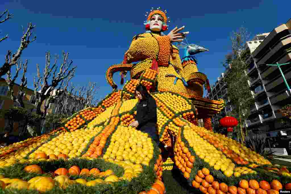 A worker puts the final touches on a sculpture made with lemons and oranges named "The Beijing Opera" during the 88th Lemon festival around the theme "Operas and dances" in Menton, France.
