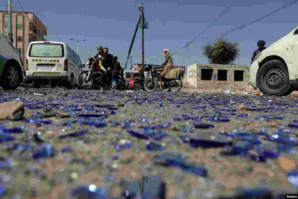 People ride on motorbikes at the scene of Saudi-led airstrike in Sana'a, Yemen.