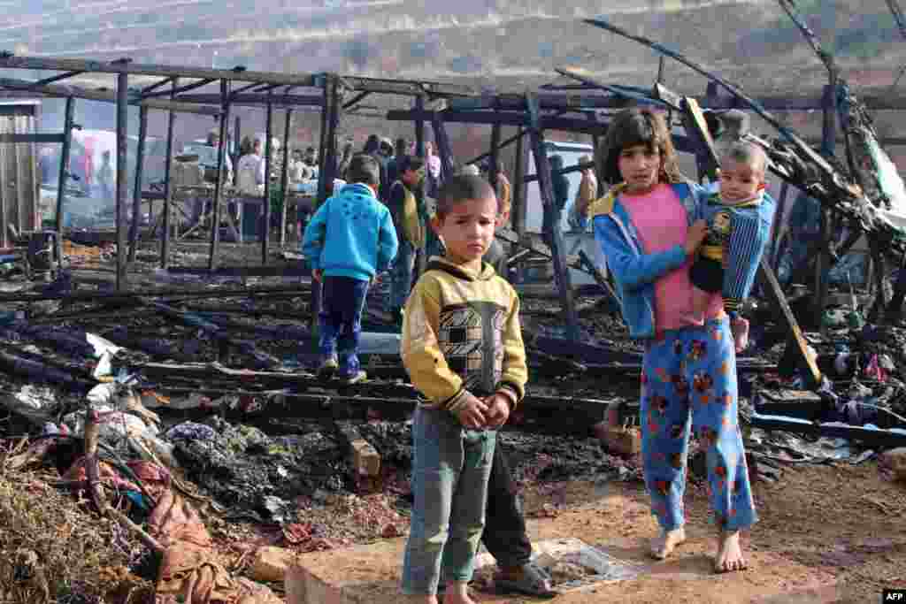 Syrian refugees check the damage following a fire that ripped through their refugee camp in the village of Yammouneh in Lebanon's eastern Bekaa Valley.
