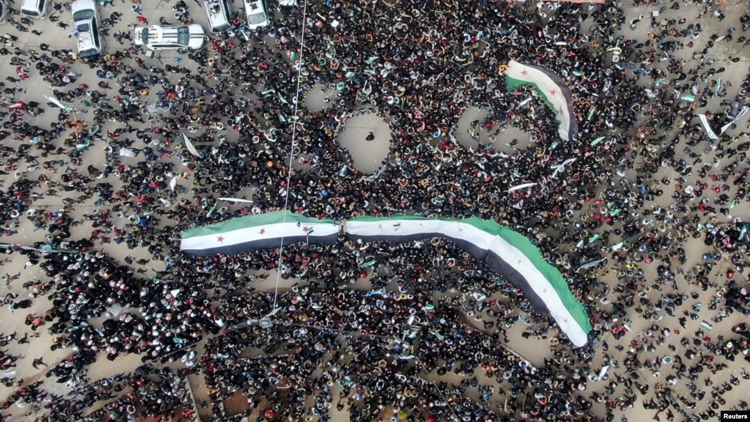 People carry Syrian opposition flags during a rally marking the 10th anniversary of the start of the Syrian conflict, in opposition-held Idlib, Syria, March 15, 2021.