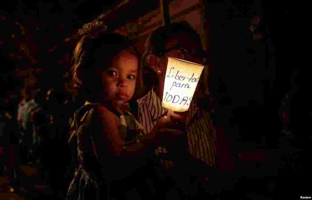 A faithful and her daughter hold a candle reading 'Freedom for all political prisoners,' during the procession of 'El Silencio' in Masaya, Nicaragua, April 18, 2019.