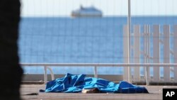 Cuerpos de víctimas cubiertos por mantas a la orilla del Mediterráneo, en Niza.