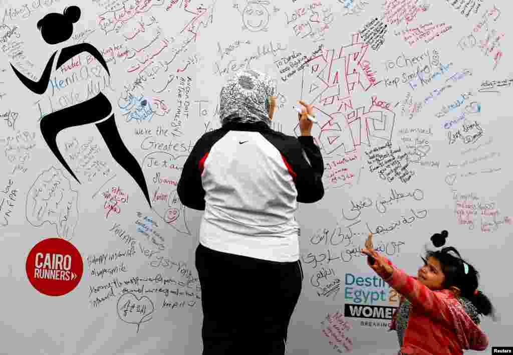 A woman, with her daughter, writes a message of support during the first Egyptian womens' race, to raise awareness about violence against women, in Cairo, Egypt.