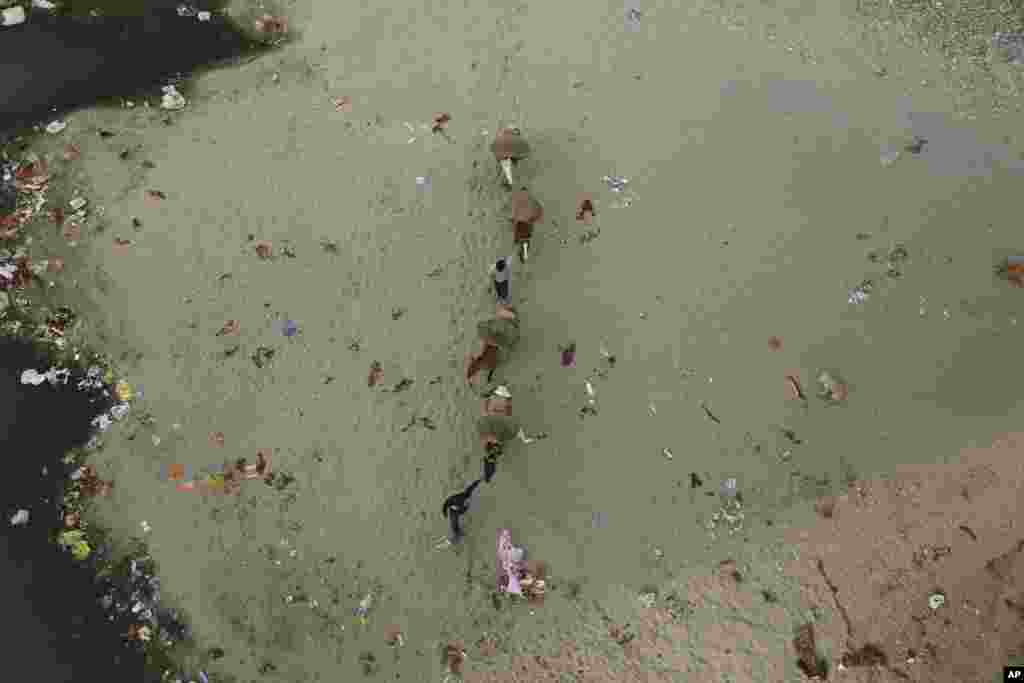 Men collect sand from the polluted banks of the River Tawi in Jammu, India.