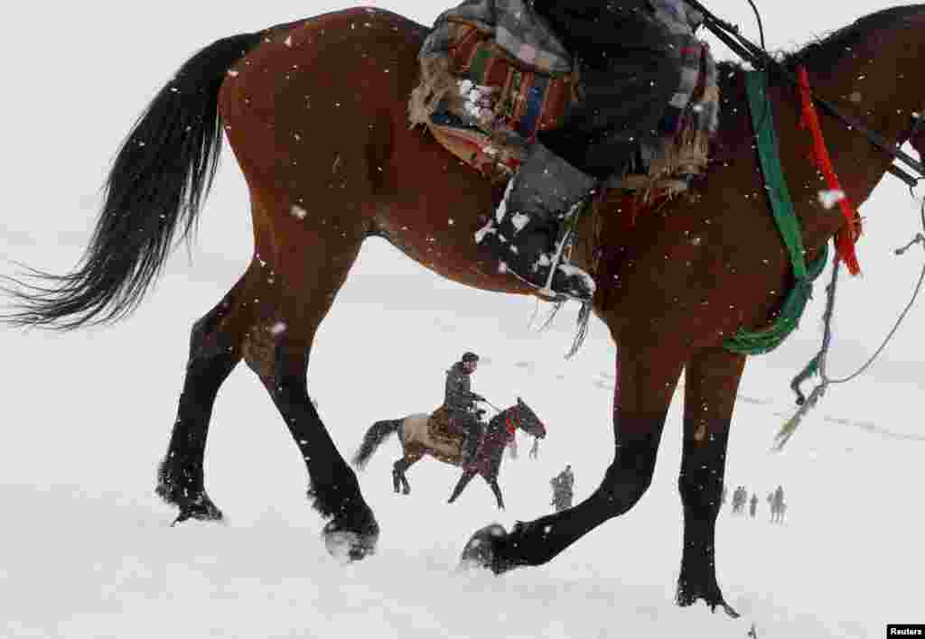 Afghan men ride horses on the snow-covered ground on the outskirts of Kabul.