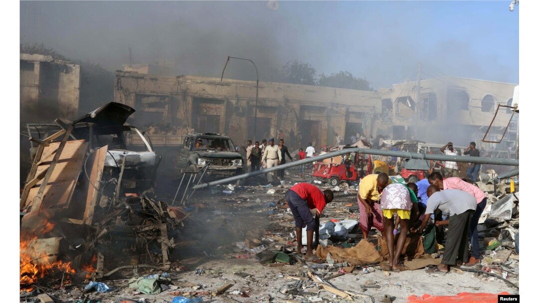 Civilians prepare to carry the dead body of an unidentified man from the scene of an explosion in KM4 street in the Hodan district of Mogadishu, Oct. 14, 2017.