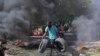 Haitiano carrega pneus para serem colocados numa barricada em chamas para impedir que membros de gangues entrem no seu bairro, em Porto Príncipe, Haiti, a 19 de novembro de 2024.