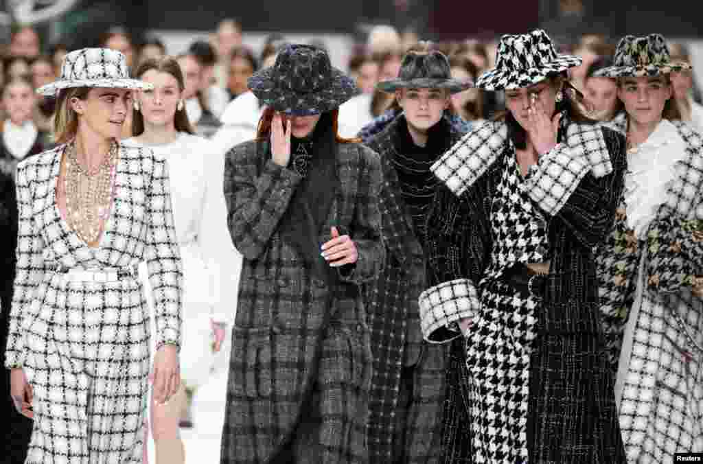 Models react while presenting creations by late designer Karl Lagerfeld as part of his Fall/Winter 2019-2020 women's ready-to-wear collection show for fashion house Chanel at the Grand Palais during Paris Fashion Week in Paris, France.