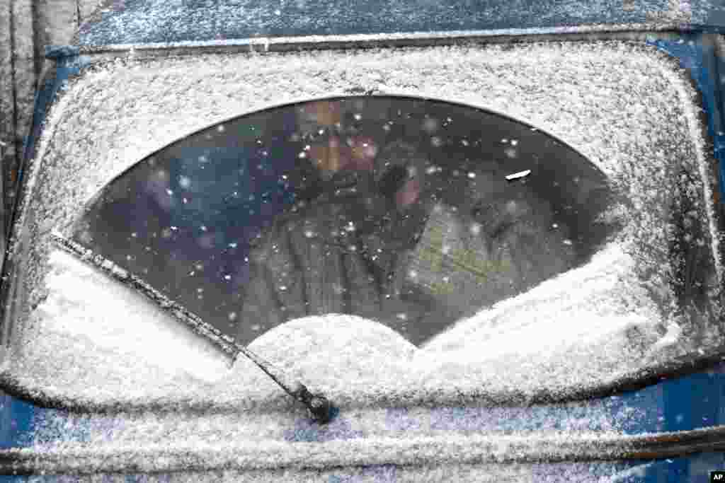 An auto-rickshaw driver looks out from the snow-covered windshield of his vehicle as the fresh snow falls in Srinagar, Indian controlled Kashmir.