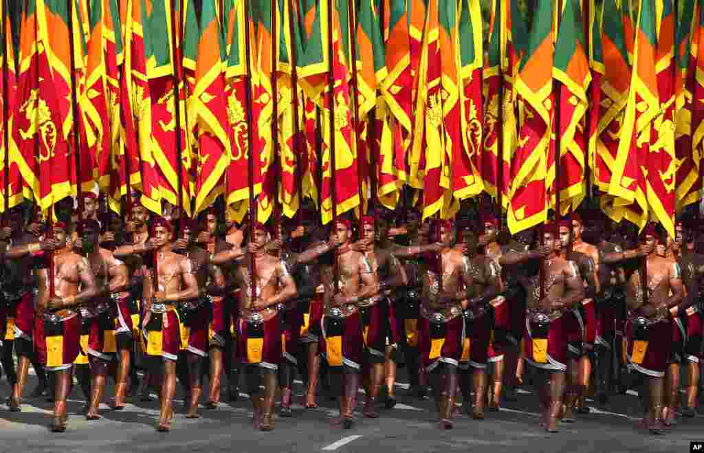 Sri Lankan soldiers dressed in traditional costumes carry national flags during the Independence Day celebration in Colombo, Sri Lanka.