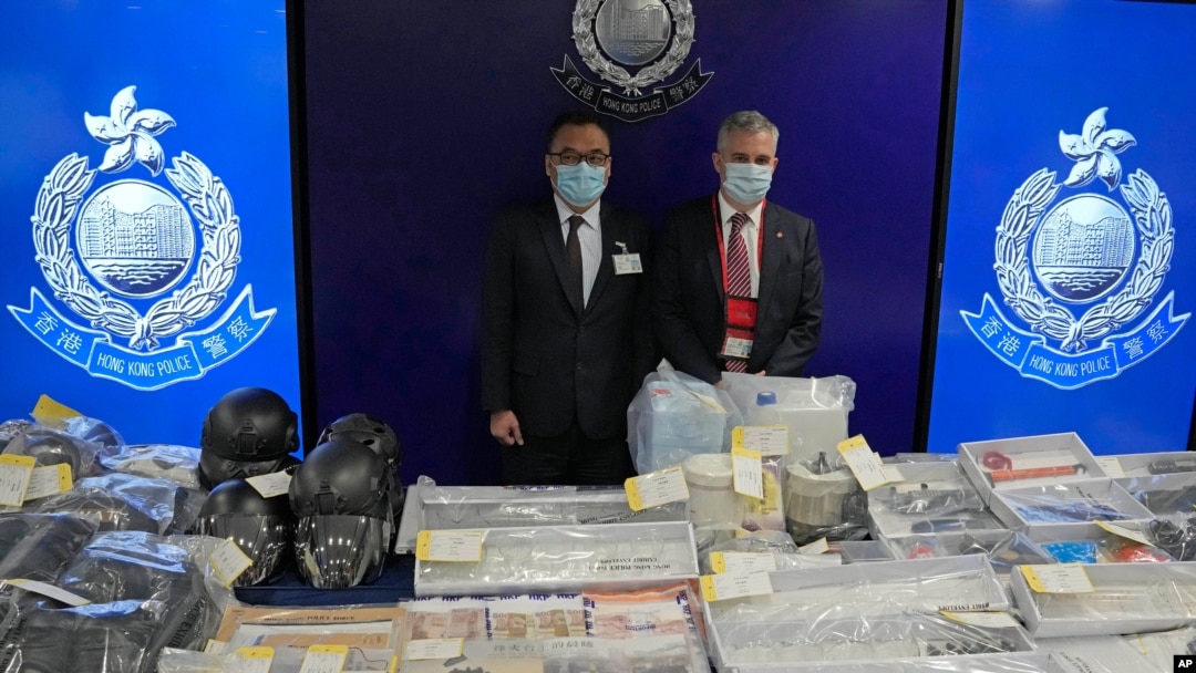 Senior Superintendent Li Kwai-wah, left, of Hong Kong Police National Security Department, and senior bomb disposal officer Alick McWhirter, right of Explosive Ordnance Disposal Bureau, pose with the confiscated evidence during a news conference.