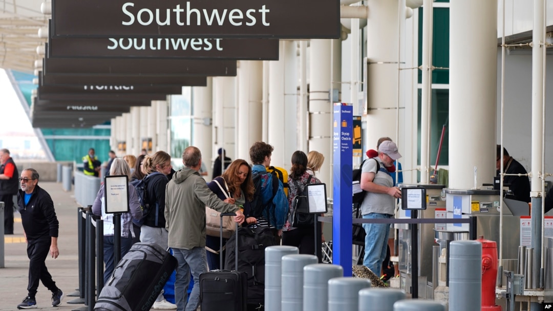 ARCHIVO: Los viajeros revisan sus equipajes en la acera de Southwest Airlines el martes 16 de abril de 2024, afuera del Aeropuerto Internacional de Denver, en Colorado. Southwest es la única de las seis grandes aerolíneas que no apoya la demanda del sector contra el gobierno.