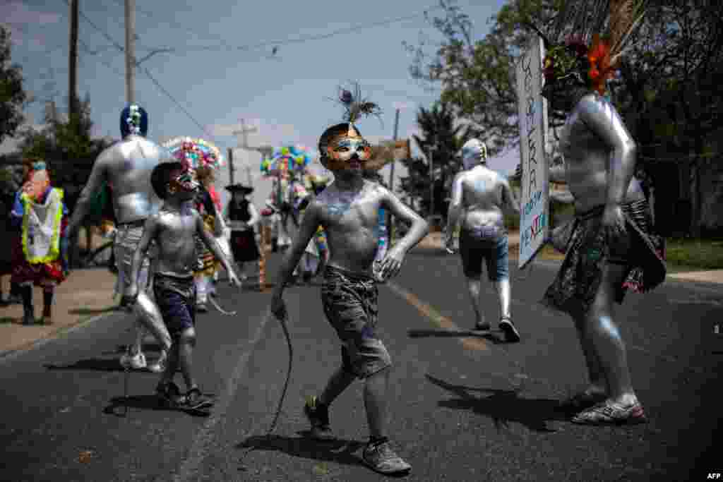 Young residents of San Nicolas de los Ranchos community in Puebla state, Mexico, with their bodies painted with oil and using masks parade and dance as "Xinacates" in the town's traditional carnival, March 31, 2019.