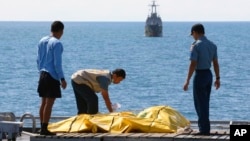 Crew members inspect bags containing bodies believed to be victims of AirAsia Flight 8501 on the deck of Indonesian Navy ship KRI Banda Aceh, on the Java Sea, Indonesia, Friday, Jan. 23, 2015. 