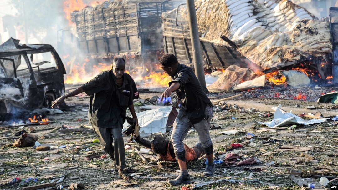 Two men carry the body of a victim following the explosion of a truck bomb in the center of Mogadishu, on Oct. 14, 2017.