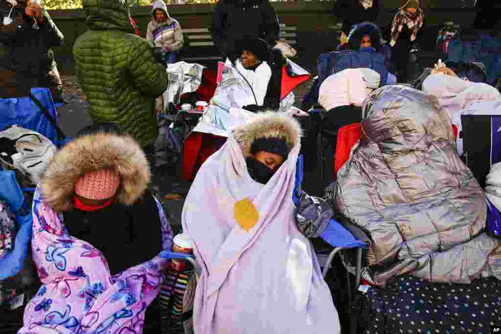 People try to stay warm as they wait for the start of the 92nd annual Macy's Thanksgiving Day Parade in New York.