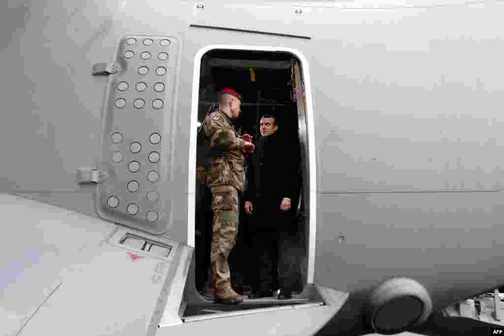 French President Emmanuel Macron (R) appears at the door of a military troop transport aircraft as he meets with infantry paratroopers during a visit to deliver his 2019 New Year's wishes to the military forces, at the air force base 101 Toulouse-Francazal, near Toulouse, southern France.