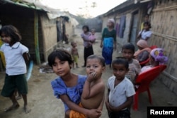 FILE - A Rohingya refugee girl carries a baby inside a refugee camp in Sitwe, in the state of Rakhine, Myanmar, March 4, 2017.