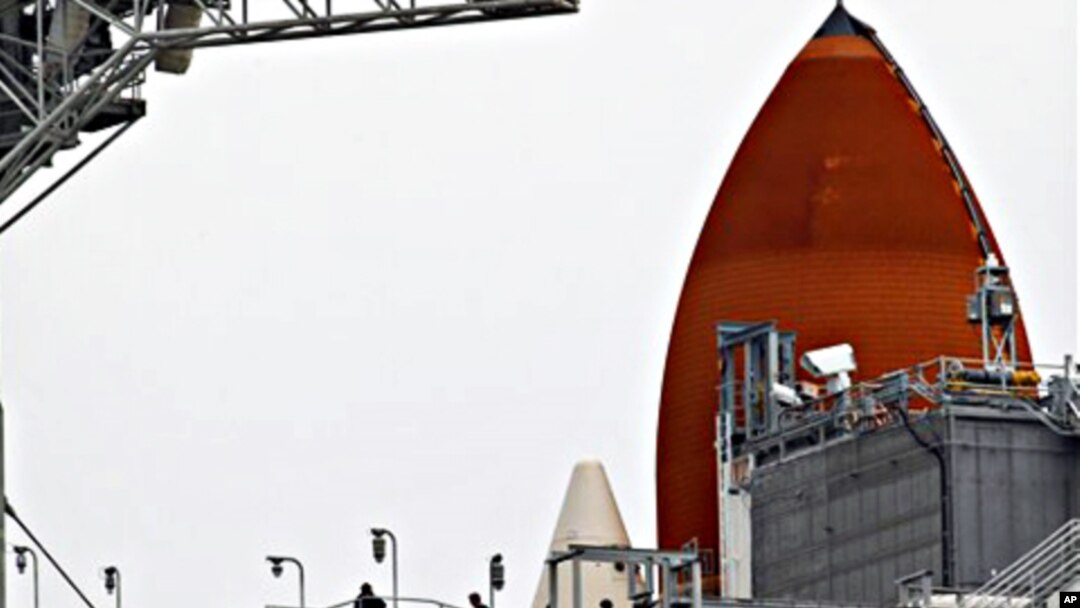 NASA workers walk near the external tank, rear, of the space shuttle Discovery at the Kennedy Space Center in Cape Canaveral, Florida, February 23, 2011