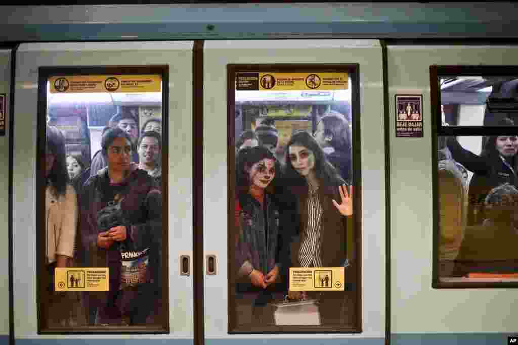 Young women, with their faces painted as a clown and zombie for Halloween, travel in the subway in Santiago, Chile, Oct. 30, 2018.