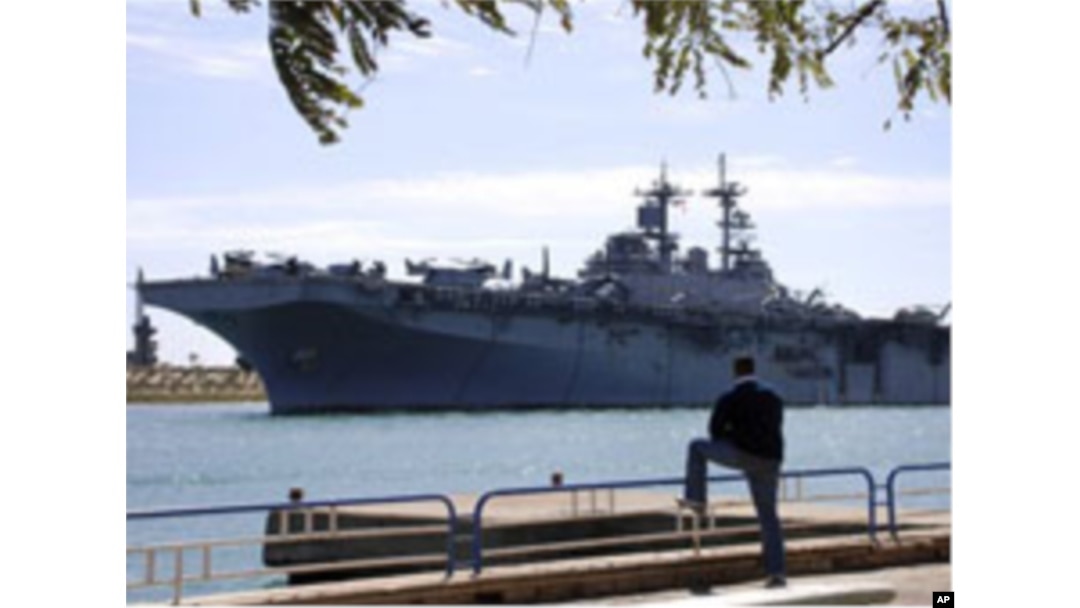 An Egyptian watches US amphibious assault ships USS Kearsarge as it sails at the Suez canal in Ismailia , Egypt, March 2, 2011