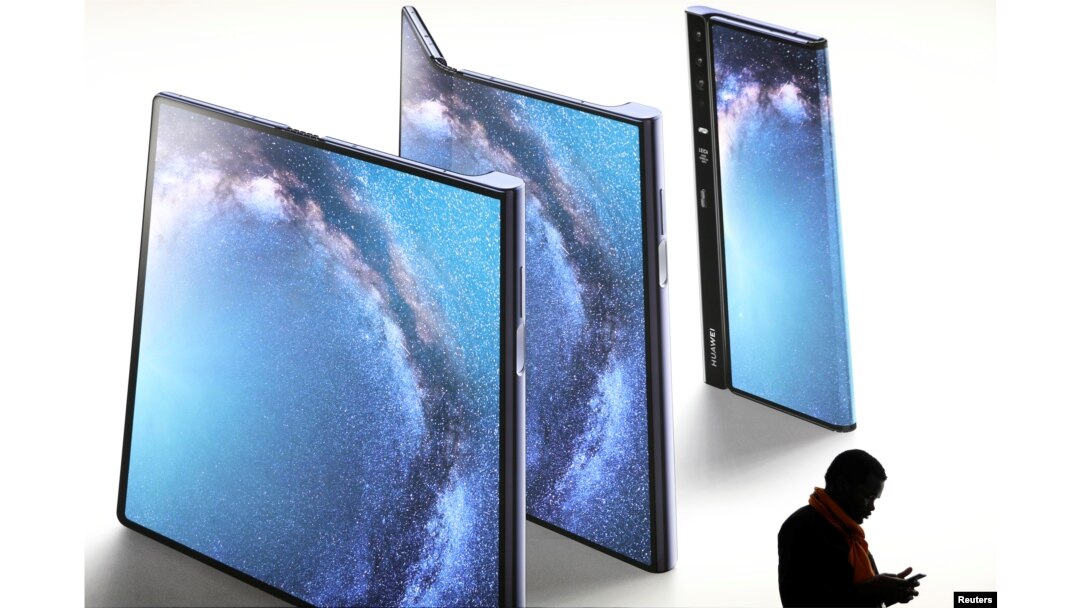 A man checks his phone next to an advertisement of a new Huawei Mate X device at the Mobile World Congress in Barcelona, Spain, Feb. 26, 2019.
