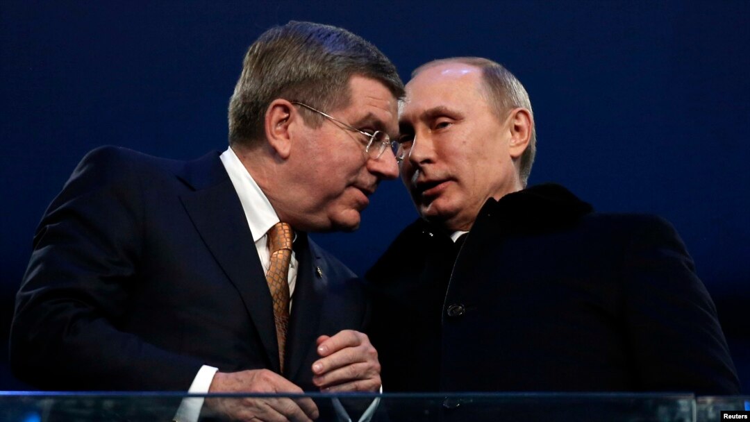 International Olympic Committee President Thomas Bach of Germany talks to Russian President Vladimir Putin during the opening ceremony of the 2014 Sochi Winter Olympics, Feb. 7, 2014.