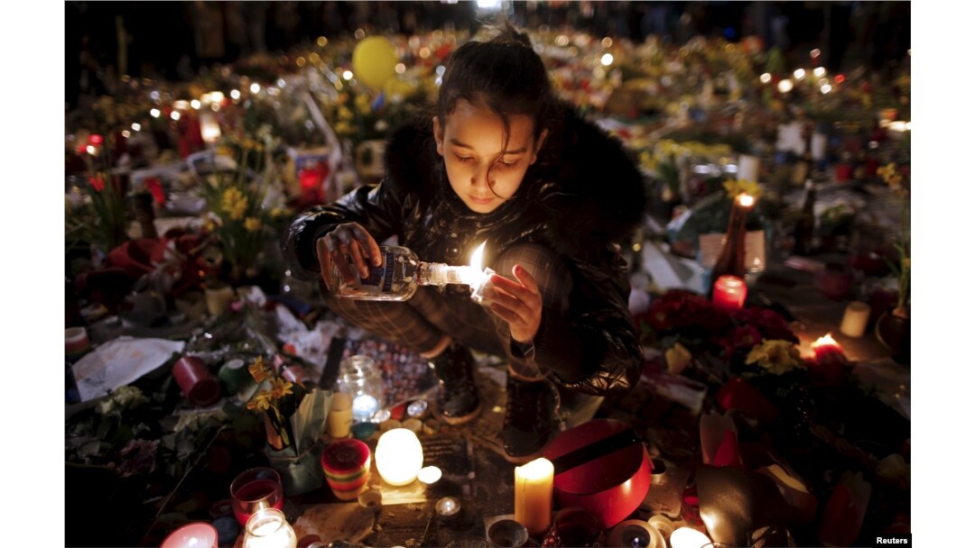 A girl lights candles as people pay tribute to the victims of Tuesday's bomb attacks, at the Place de la Bourse in Brussels, Belgium, March 26, 2016.