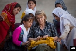 FILE - AP Special Regional Correspondent for Afghanistan and Pakistan Kathy Gannon sits with girls at a school in Kandahar, Afghanistan, Oct. 1, 2011.