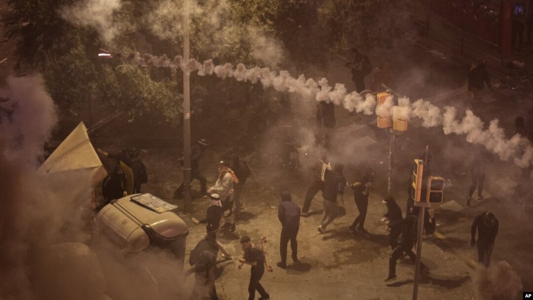 Manifestantes se alejan del gas lacrimógeno arrojado por la policía nacional durante enfrentamientos en Barcelona. (AP)