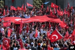 FILE - Turkish citizens wave their national flags as they protest against the military coup outside Turkey's parliament near the Turkish military headquarters in Ankara, Turkey, Saturday, July 16, 2016.