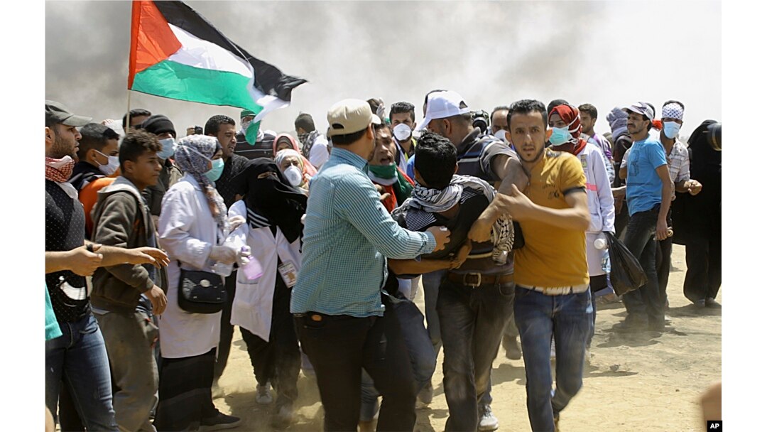 Palestinian protesters evacuate a wounded youth near the Israeli border fence, east of Khan Younis, in the Gaza Strip, May 14, 2018.