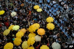 FILE - Protesters holding yellow umbrellas gather to observe a moment of silence to mark the first anniversary of "Umbrella Movement" outside the government headquarters in Hong Kong, Sept. 28, 2015.
