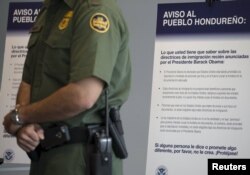Un agente de aduanas hace guardia frente a un anuncio que advierte contra el ingreso ilegal a Estados Unidos en el puesto fronterizo de San Ysidro, California.