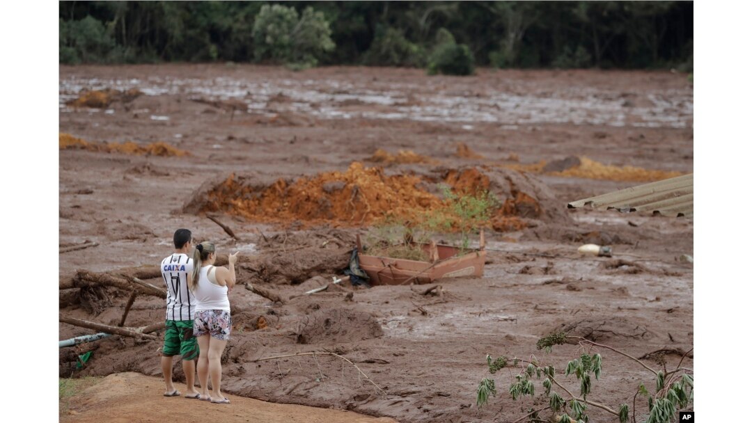 A couple with missing relatives look at the flooded area, after a dam collapsed in Brumadinho, Brazil, Jan. 26, 2019.