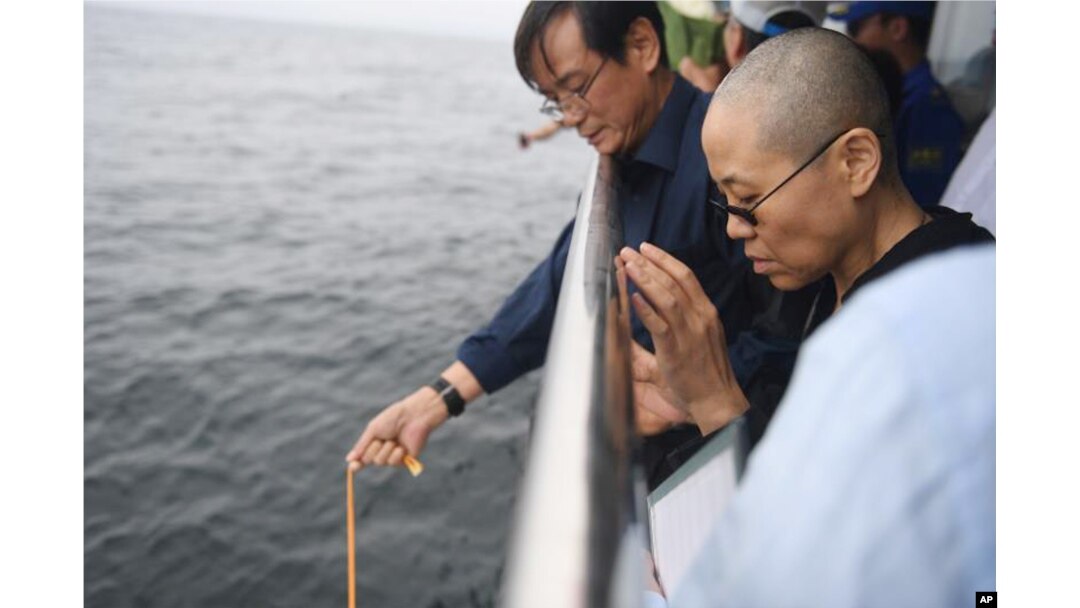 In this photo provided by the Shenyang Municipal Information Office, Liu Xia, the wife of Chinese Nobel Peace Prize laureate Liu Xiaobo, watches as Liu's ashes are buried at sea off the coast of Dalian in northeastern China's Liaoning Province, July 15, 2017.
