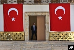 A Turkish parliament security man stands guard next to the broken yellow copper doors laid on the ground at the entrance of the assembly hall at the parliament building which was attacked by the Turkish warplanes during the failed military coup last Friday.