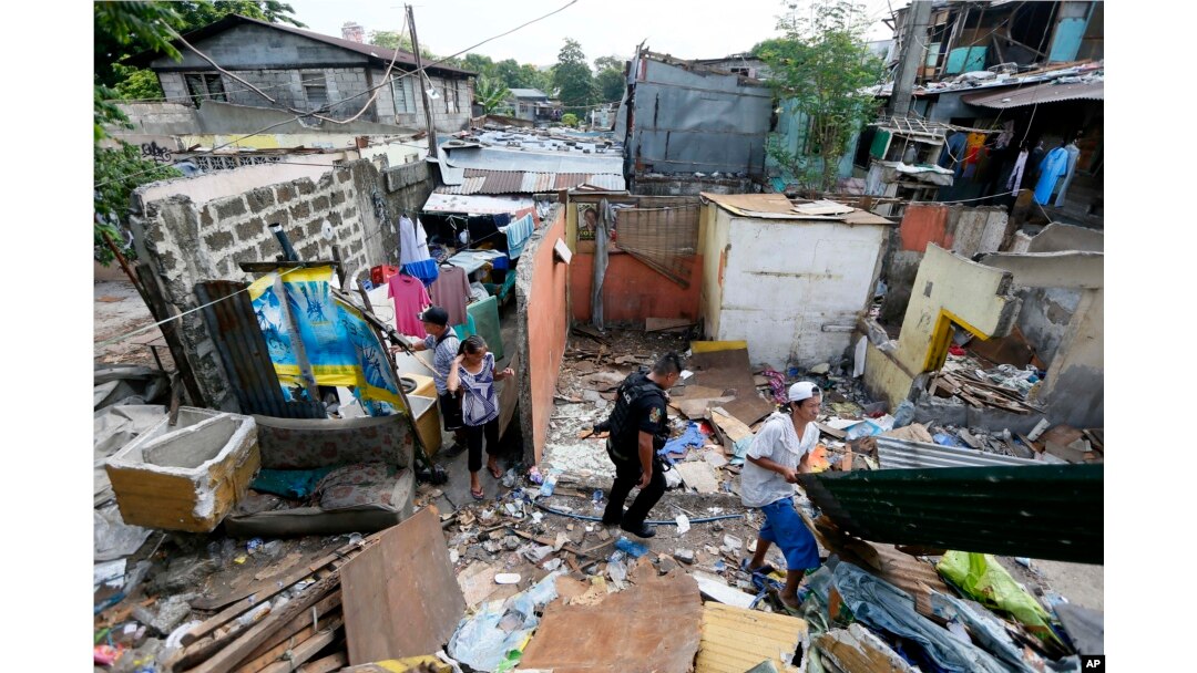 A member of the Philippine National Police SWAT team walks through debris as former inhabitants try to salvage any items following the demolition of their community Monday, June 6, 2016 in suburban Quezon city northeast of Manila, Philippines.