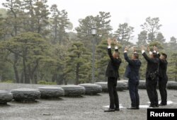 People raise hands as they shout 'banzai', or cheers, facing the Imperial Palace on the day of the Emperor Akihito's abdication in Tokyo, April 30, 2019.