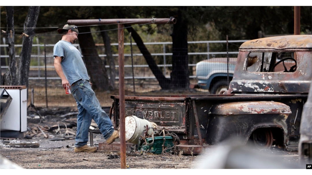 Gary Herrin angrily kicks at an old Chevrolet pickup truck destroyed in a wildfire several days earlier as he visits the family home for the first time since it burned down, Sept. 15, 2015, in Middletown, Calif.