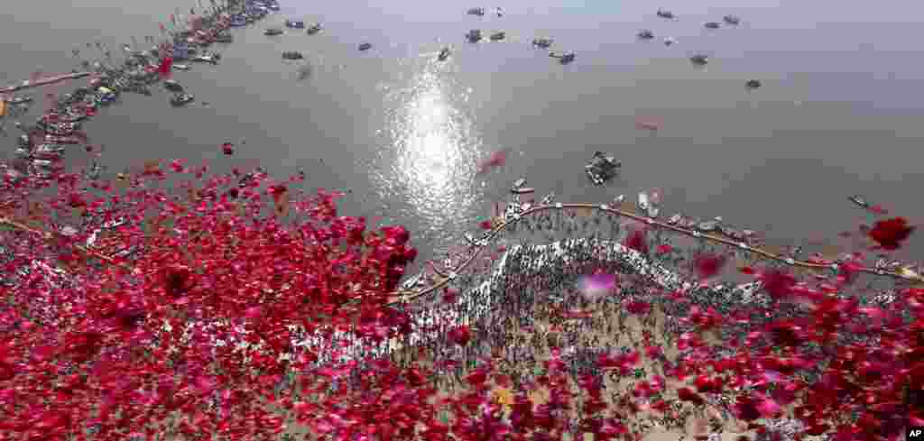 Uttar Pradesh government officials throw rose petals from a helicopter on devotees taking ritualistic dips at Sangam, on the auspicious day of "Paush Purnima" during Kumbh Mela or Pitcher festival at Prayagraj, India.