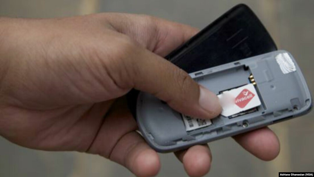 FILE - A mobile phone user checks his SIM card.