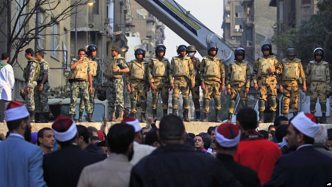 Egyptian Army soldiers stand guard atop a concrete block barricade on the street between Tahrir Square and the interior ministry in Cairo, Egypt, Nov. 24, 2011