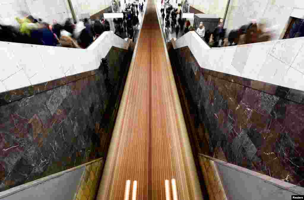 Passengers walk along a staircase as a train moves at Partizanskaya metro station in Moscow, Russia.